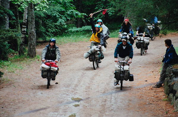 A group of cyclists with camping gear ride on a forest trail