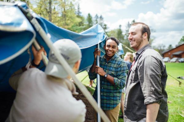 Three guys setting up lawn tent and talking