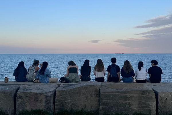 A group of students sitting and facing a lake