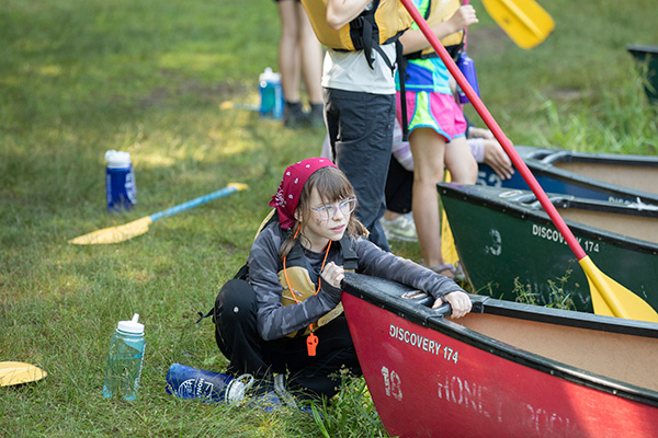 A girl sitting by a canoe