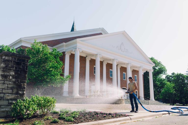 Wheaton College Landscape Operations watering flower display outside Edman Chapel