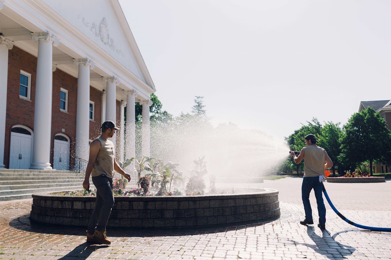 Wheaton College Landscape Operations watering flowers outside Edman Chapel