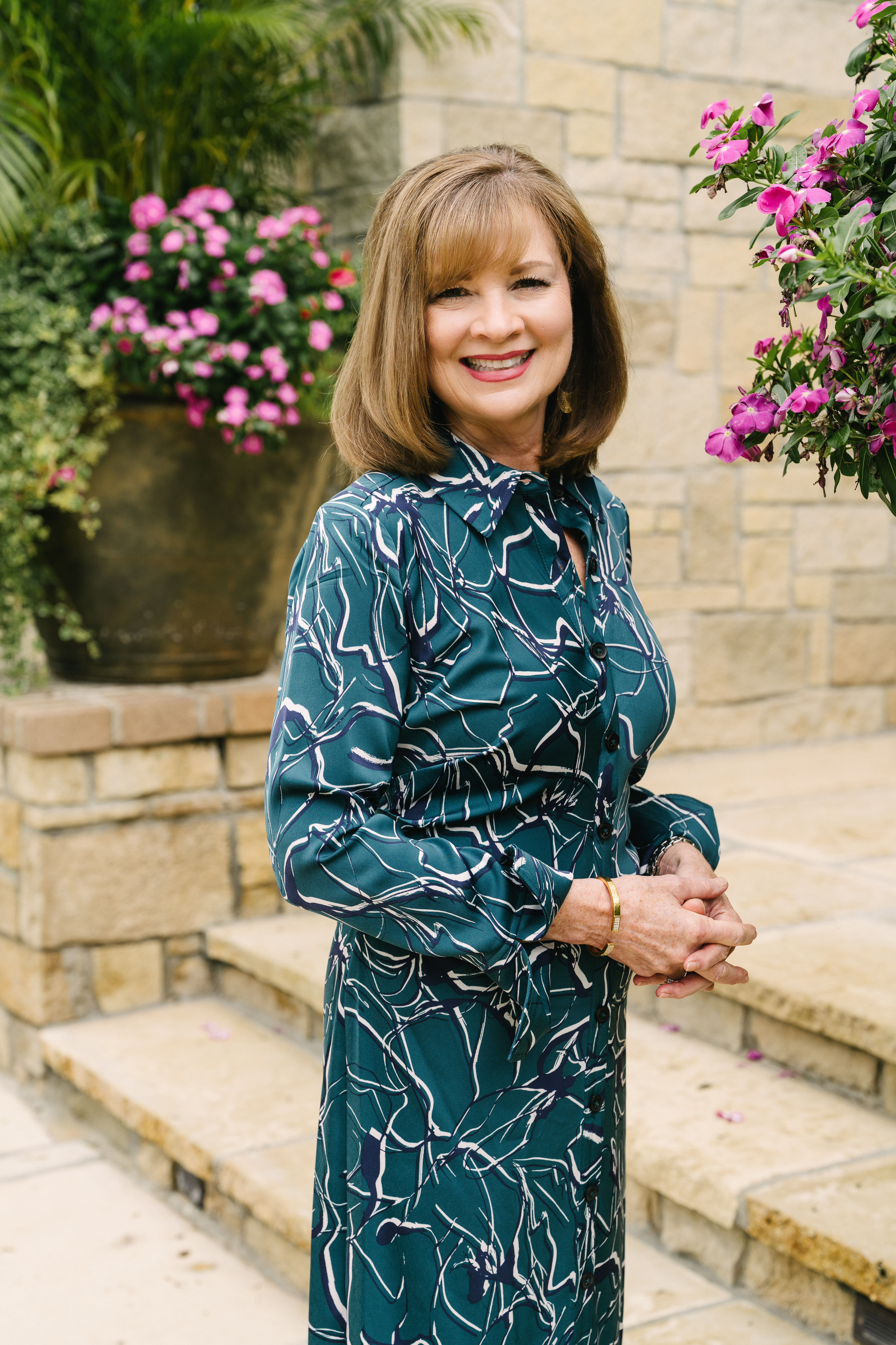 Woman in blue dress standing on steps in front of pink flowers