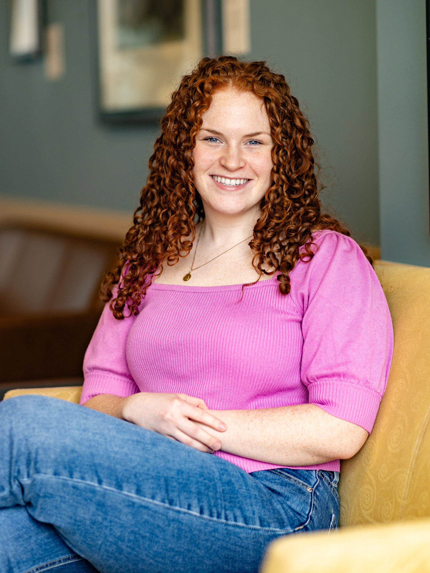 A young woman with curly auburn hair smiles