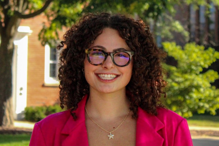 A young woman with curly brown hair smiles